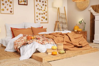 Sonbahar süslemeleri ve mumları olan şık bir yatak odası.