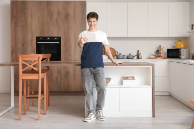 Genç adam mutfakta tablet bilgisayarla görüntülü sohbet ediyor.