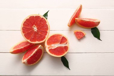 Taze greyfurtlar ve beyaz ahşap arka planda yapraklar kes