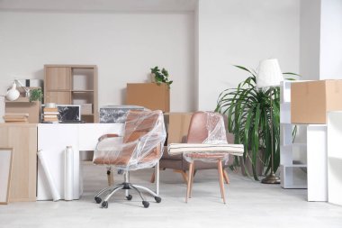 Taşınma gününde masa, kutu ve sandalyelerle dolu bir ofis.