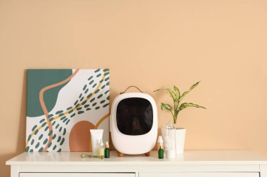 Bej duvarın yanındaki çekmecelerde cilt ürünleri bulunan kapalı küçük kozmetik buzdolabı. Yakın çekim.