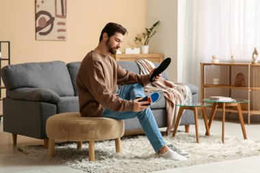 Genç adam evdeki ayağına ortopedik taban uyguluyor.