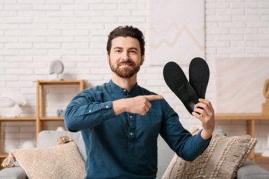 Evinde siyah ortopedik tabanlı yakışıklı bir adam.