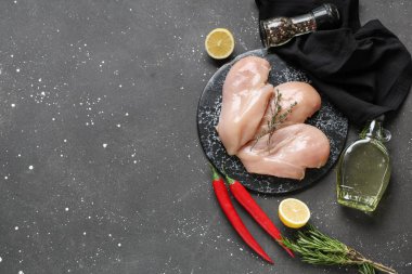 Çiğ tavuk göğsü ve siyah arka planda farklı baharatlar olan tahta.