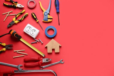 Ahşap ev modeli ve kırmızı arka planda inşaat araçları