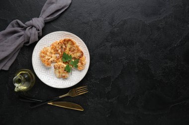 Siyah arka planda ızgara karnabahar bifteği ve maydanozlu tabak.