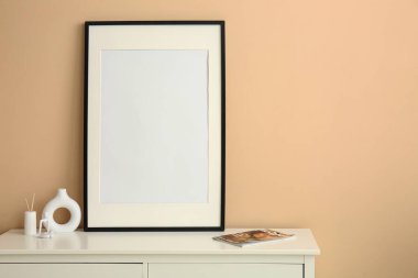 Boş fotoğraf ve bej duvarın yanındaki şarjör çerçeveli beyaz çekmeceler.