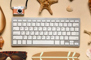 Kamera ve bej arka planda plaj dekoru olan bilgisayar klavyesi