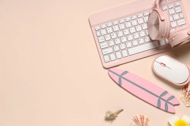 Bej arka planda kulaklıklı bilgisayar klavyesi, fare ve plaj dekoru