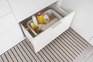 Mutfakta farklı temizlik malzemeleri, pp-toz ve süngerler olan bir sepet dolusu açık çekmece.