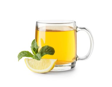 Beyaz arka planda bir parça limonlu bir bardak sıcak nane çayı.
