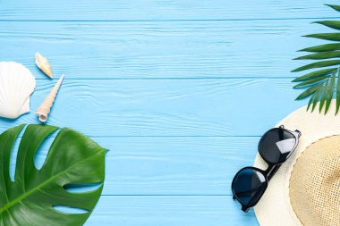 Şık güneş gözlüklü kompozisyon, hasır şapka, palmiye yaprakları ve ahşap arka planda deniz kabukları