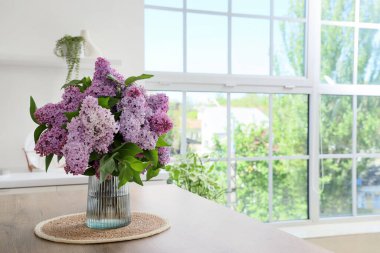 Mutfaktaki masada leylak çiçekli vazo.