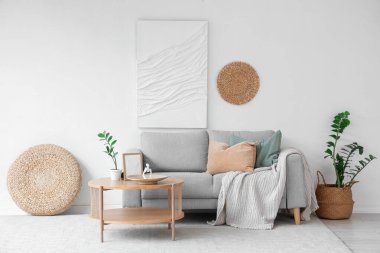 Oturma odasının iç tarafındaki beyaz duvarın yanındaki kanepe ve ahşap sehpa.