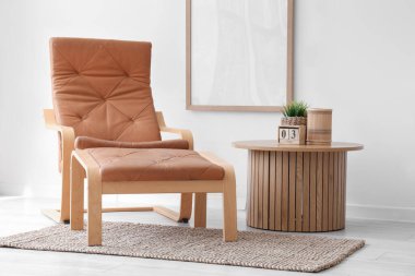 Odadaki beyaz duvarın yanında, ayaklı koltuk ve sehpa.