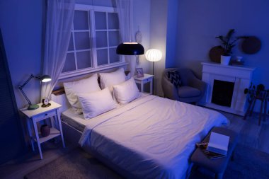 Koltuğu, şöminesi ve parlak lambaları olan karanlık yatak odasının içi.