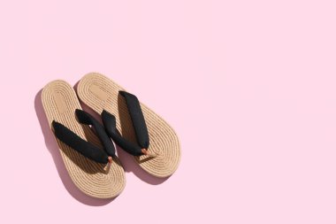 Pembe arka planda şık hasır terlikler