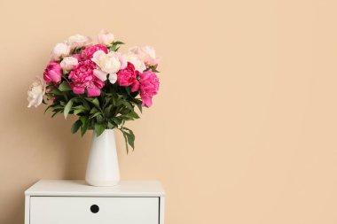 Odadaki bej duvarın yanındaki çekmecelerin üzerinde güzel şakayık çiçekleri olan vazo, yakın plan.