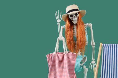 Yeşil arka planda peruklu ve plaj aksesuarlı insan iskeleti. Yaz tatili kavramı