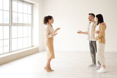 Kadın emlakçı hamile çifte yeni evi gösteriyor.