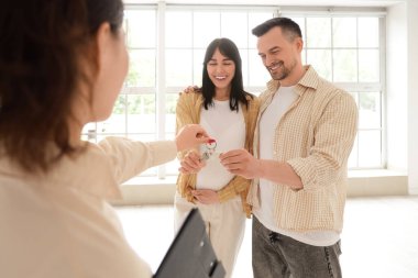 Yeni evlerinde emlakçıdan anahtar alan genç bir çift.