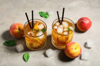 Gri grunge arka planda lezzetli şeftalili buzlu çay, yakın plan.