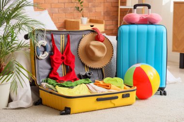 Yatak odasında plaj aksesuarları olan bavullar.