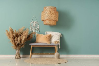 Gri bank, yastıklar ve vazo. Salonun içinde otlar var.