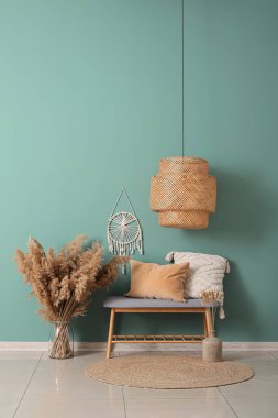 Gri bank, yastıklar ve vazo. Salonun içinde otlar var.