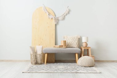 Gri bank, puf, katlanan ekran ve merdiven, koridorun iç tarafındaki beyaz duvarın yanında.