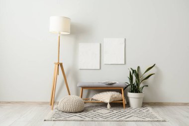 Gri bank, zemin lambası, pouf ve saksı salonun içinde.