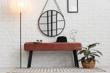 Pembe bank, yer lambası, ayna ve ev bitkisi odanın içinde.