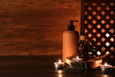 Ekranlı kompozisyon, yanan mumlar ve ahşap arka planda bulunan kozmetik ürünler, yakın plan