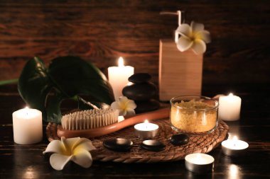 Kaplıca taşlı hasır, masaj vücut fırçası ve ahşap arka planda yanan mumlar, yakın plan.