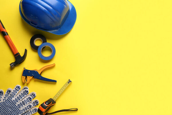 Жесткая шляпа и строительные инструменты на желтом фоне