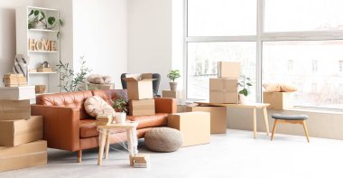 Taşındığı gün oturma odasında masa ve karton kutular olan kanepe