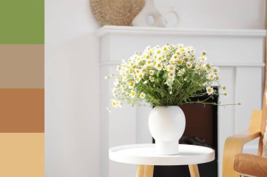 Oturma odasındaki masada papatya çayı olan vazo. Farklı renk desenleri