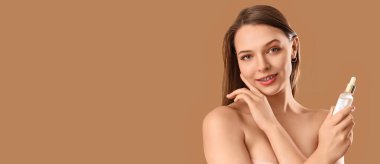 Bej arka planda kozmetik serumu olan güzel genç bir kadın.