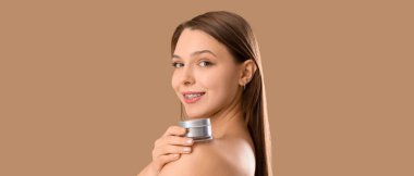 Bej arka planda kozmetik kremi olan güzel genç bir kadın. 