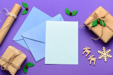 Zarflı boş kağıt, Noel süsü ve mor arka planda hediyeler. Noel Baba 'ya mektup