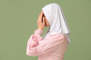 Genç Müslüman kadın yeşil arka planda dua ediyor