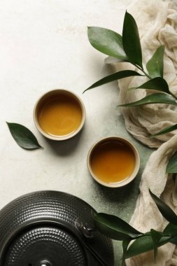 Çaydanlık ve fincanlar yeşil çay ve gri grunge arka planda yapraklar