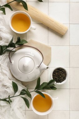 Çaydanlıklı kompozisyon, kuru yapraklı kase ve beyaz fayanslı çay fincanları.