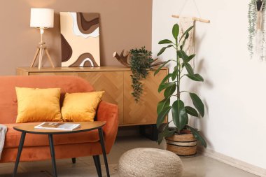 Turuncu kanepeli, kahve masalı ve çiçekli şık bir oda.