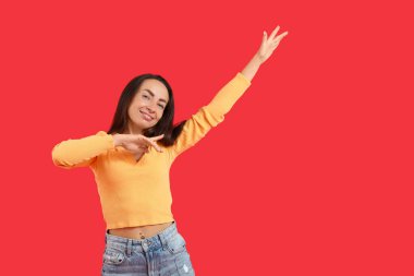 Kırmızı arka planda dans eden mutlu orta yaşlı kadın