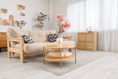 Masada vazo içinde kanepe, çekmece ve manolya çiçekleri olan oturma odasının içinde.