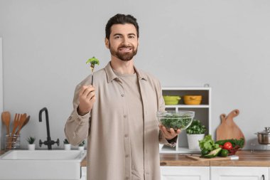 Yakışıklı adam mutfakta avokadoyla lezzetli lahana salatası yiyor.