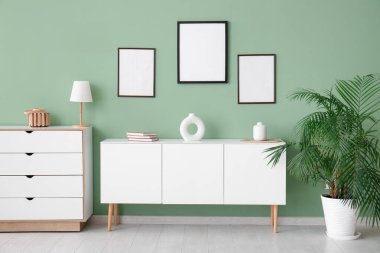 Oturma odasındaki yeşil duvardaki boş fotoğraf çerçeveleri.