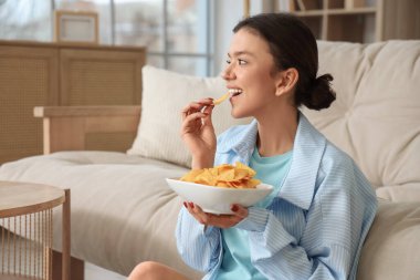 Genç kız evde lezzetli cipsler yiyor.