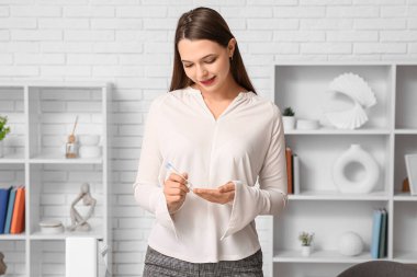 Genç diyabetik kadın ofisinde tükenmez kalemle kan örneği alıyor.